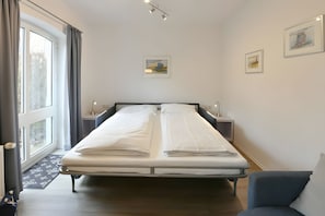 A hotel room with a large bed, bedside tables, a desk, and a chair. - Comfortable, Modern Apartment in a Central, Quiet Island Location for 2 Guests (Wangerooge)