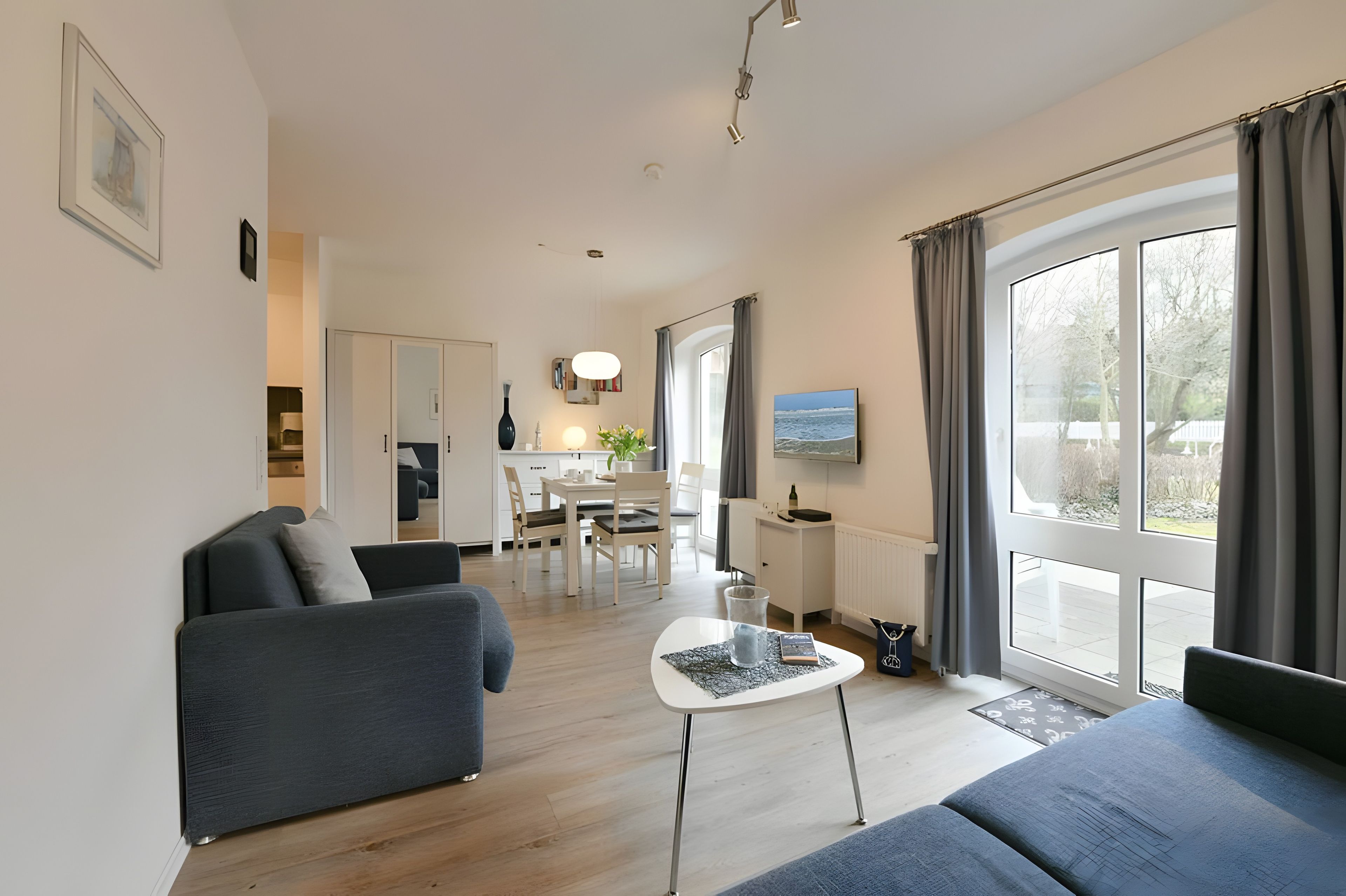 A modern living room with a sofa, a coffee table, and a dining area with a table and chairs.