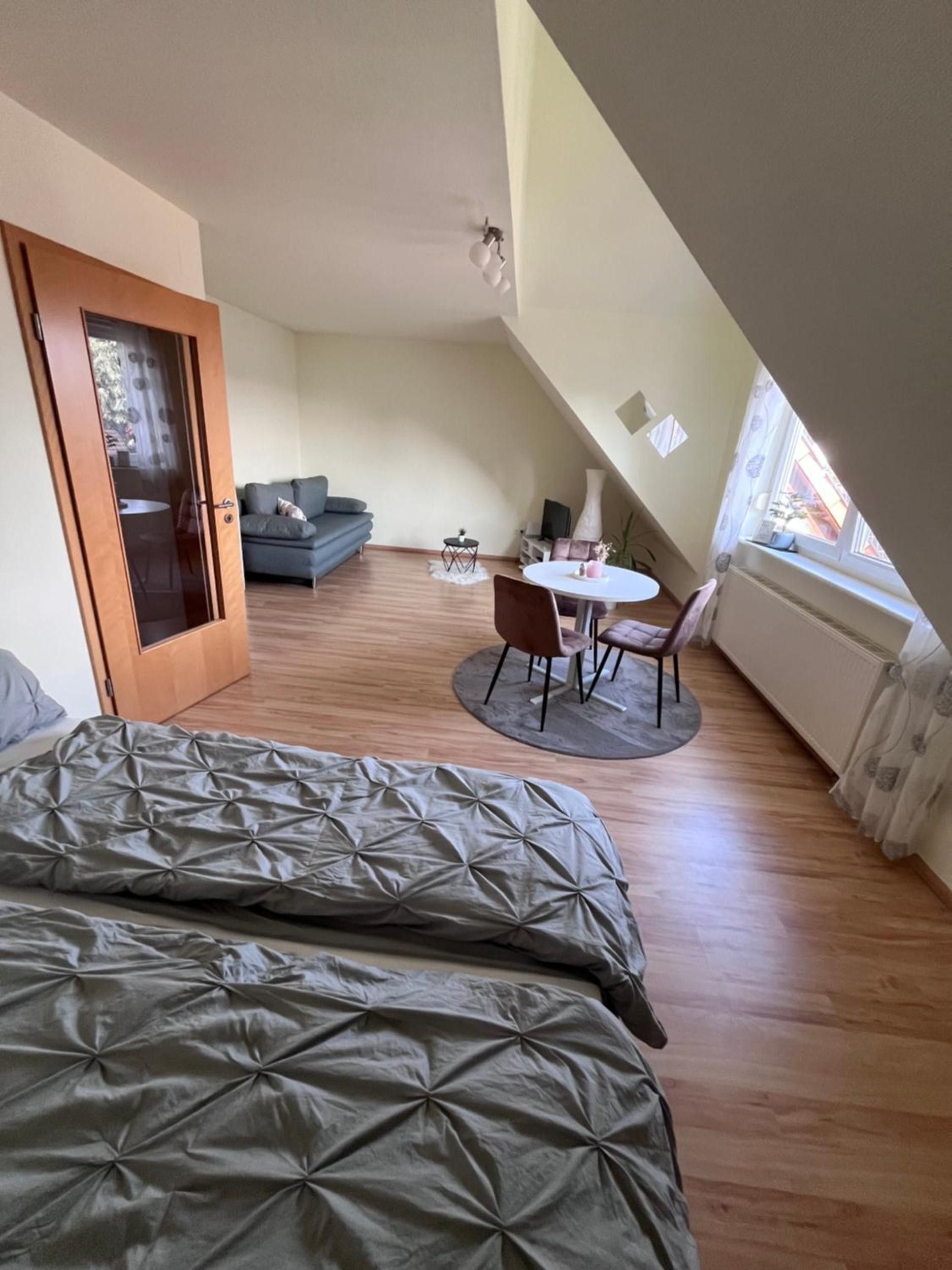 Ein Schlafzimmer mit einem Bett, einem kleinen runden Tisch mit Stühlen, einem Sofa und einer Tür zu einem anderen Raum.