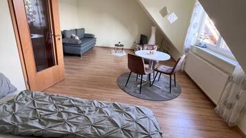 Ein Schlafzimmer mit einem Bett, einem kleinen runden Tisch mit Stühlen, einem Sofa und einer Tür zu einem anderen Raum.
