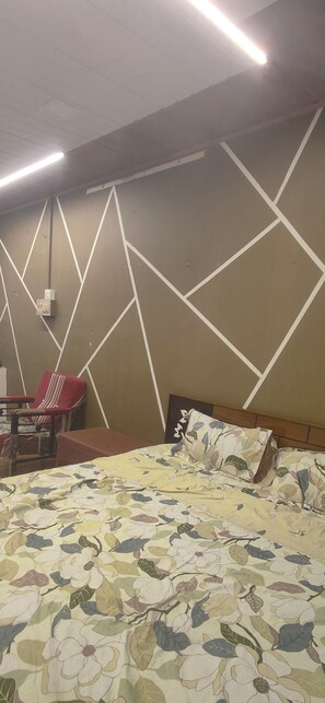 Une chambre d ’hôtel avec un lit, une chaise et un mur orné de motifs géométriques.