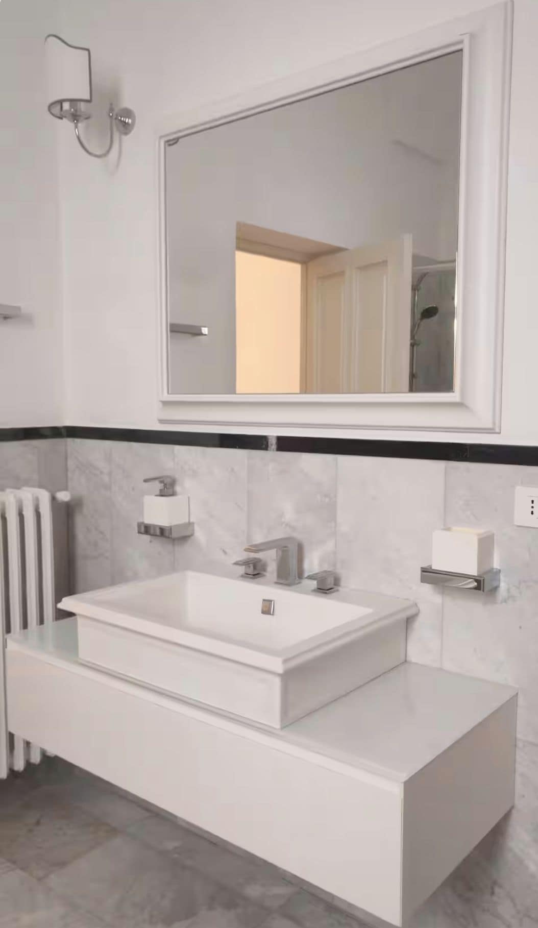 A modern bathroom with a large rectangular sink, a wall-mounted mirror, and a towel rack.