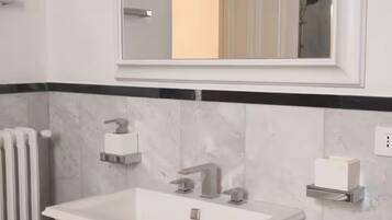 A modern bathroom with a large rectangular sink, a wall-mounted mirror, and a towel rack.