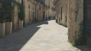 A narrow street with historic buildings, a paved walkway, and a clear sky.
