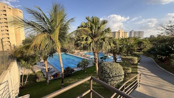 Área residencial com piscina, palmeiras e um calçadão.