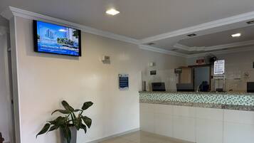 A reception area with a flat-screen TV displaying a property, a reception desk, and a potted plant.