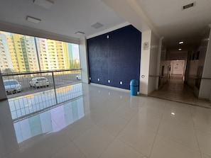 A spacious indoor area with a balcony overlooking parked cars and a high-rise building. - CRCN - Caldas Novas Flat (Caldas Novas)