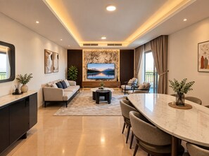 A modern living room with a sofa, a TV, a dining table, and a kitchen area. - Vesta Luxury APT - 2Br - cfc xc (New Cairo)