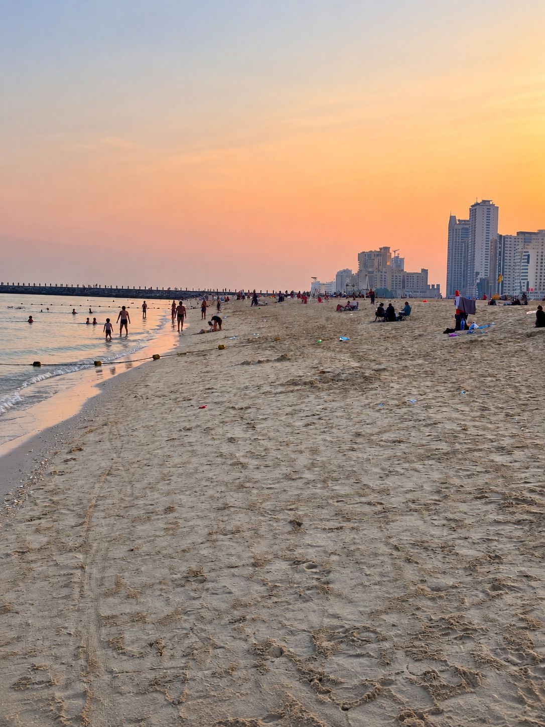 Una spiaggia con persone, un molo e edifici sullo sfondo.