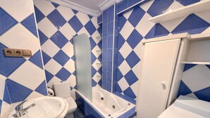 A bathroom with a sink, toilet, bathtub, and a mirror. - Vrbo Property (Torremolinos)