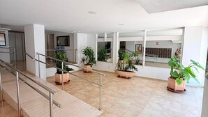 A spacious indoor area with a marble floor, a metal staircase with handrails, and several potted plants. - Vrbo Property (Torremolinos)
