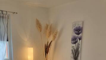 Ein modernes Wohnzimmer mit einer Eckcouch, einem Esstisch mit Stühlen, einem violetten Teppich und einer hohen Stehlampe.