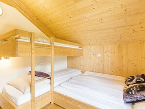 A bunk bed room with wooden walls and a sloped ceiling. - One-bedroom Cabin (Sankt Georgen am Kreischberg)