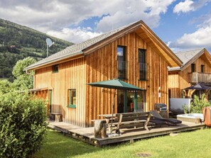 A wooden cabin with a deck, outdoor seating, and a hot tub. - One-bedroom Cabin (Sankt Georgen am Kreischberg)