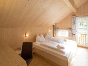 A wooden cabin bedroom with a bed, a bench, and a window with curtains. - One-bedroom Cabin (Sankt Georgen am Kreischberg)