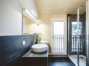 A modern bathroom with a wooden ceiling, a large mirror, two sinks, and a glass-enclosed shower area. - One-bedroom Cabin (Sankt Georgen am Kreischberg)