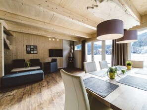 A modern interior with a wooden ceiling, a dining area with a table and chairs, a sofa, and a fireplace. - One-bedroom Cabin (Sankt Georgen am Kreischberg)