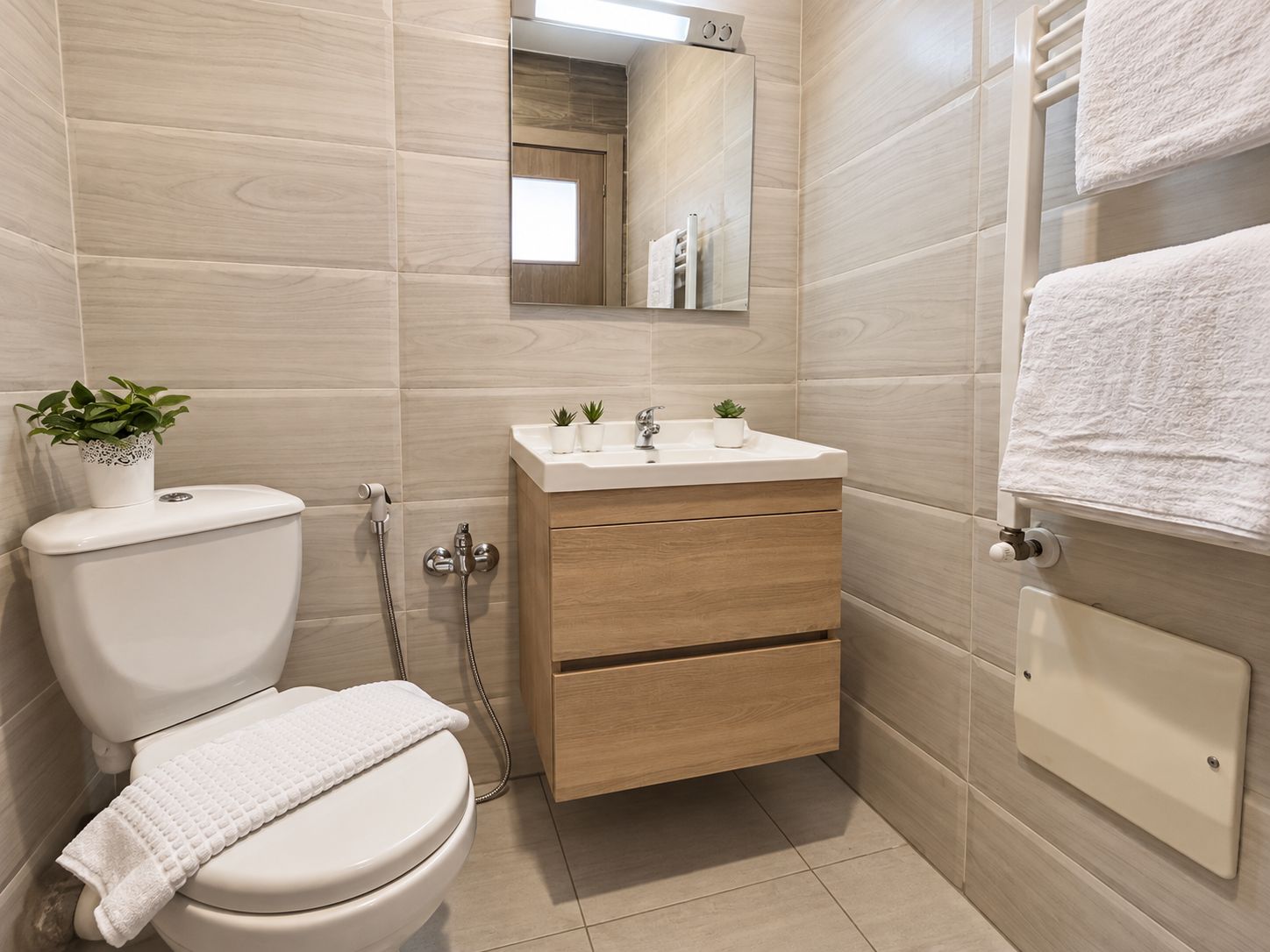A modern bathroom with a toilet, sink, and mirror.
