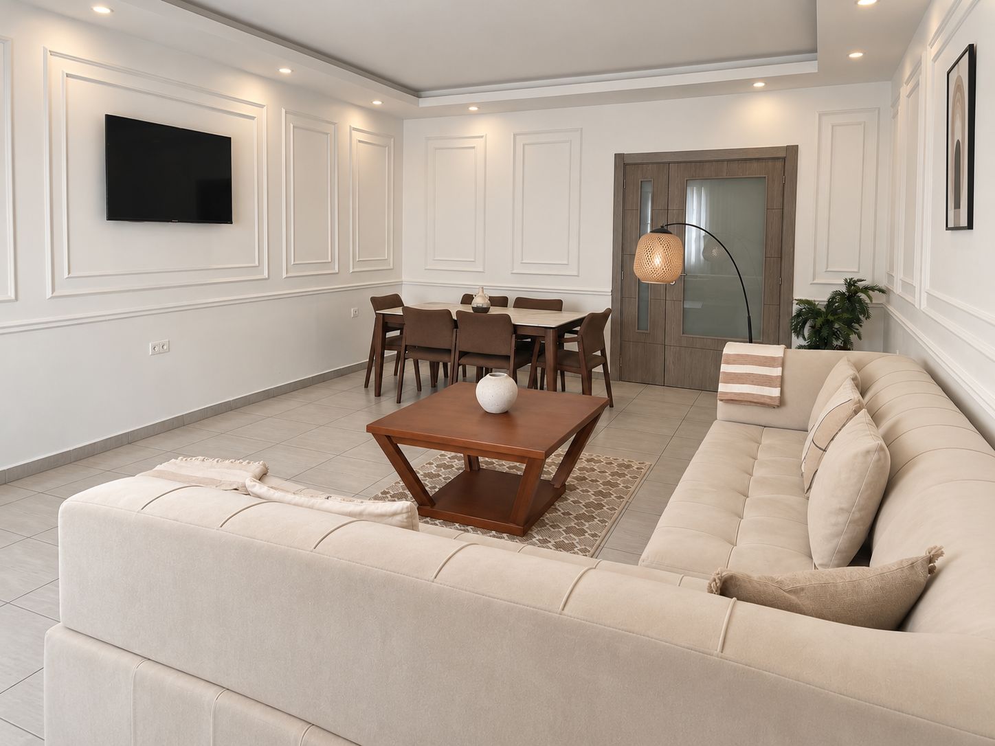 Una sala de estar moderna con un sofá color beige, una mesa de centro de madera y un comedor con mesa y sillas.