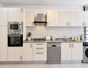 Una cocina moderna con electrodomésticos de acero inoxidable, armarios de madera clara y encimera de granito.