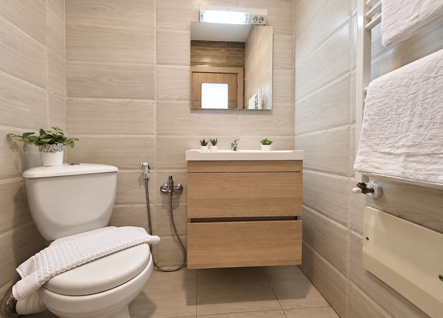 Une salle de bain moderne avec des toilettes, un lavabo surmonté d’un miroir et une serviette accrochée au mur.