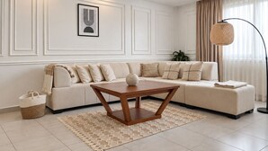 A modern living room with a sectional sofa, a wooden coffee table, a woven basket, and a floor lamp. - Spacieux 3 chambres Boulevard des Lions (Bir El Djir)