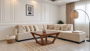 Una sala moderna con un sofá modular, una mesa de centro de madera, una cesta tejida y una lámpara de pie.
