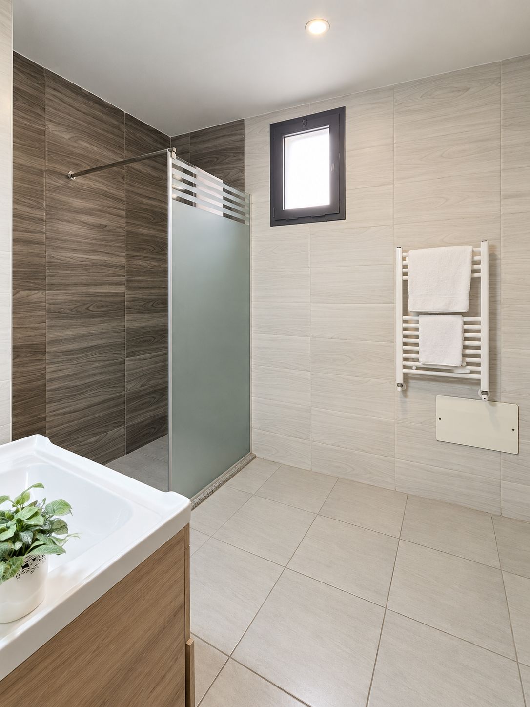 Un baño moderno con cabina de ducha, lavamanos empotrado y un perchero para toallas.