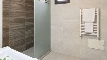 Un baño moderno con cabina de ducha, lavamanos empotrado y un perchero para toallas.