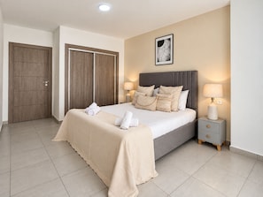Une chambre à coucher comprenant un lit, des lampes de chevet, une table de chevet, un tableau encadré au mur et une armoire.