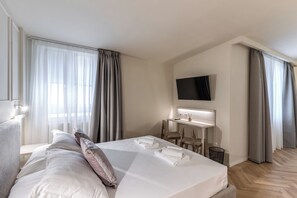 Une chambre d’hôtel équipée d’un lit, d’un bureau, d’une chaise, d’une télévision et d’une fenêtre avec des rideaux.