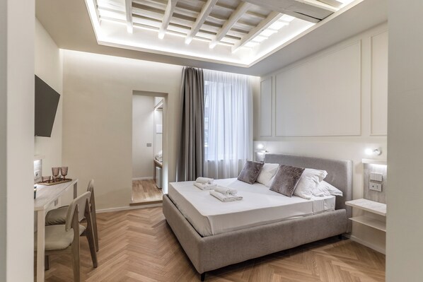 Habitación de hotel moderna con una cama grande, un escritorio con silla y un baño visible a través de una puerta abierta.