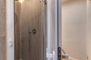 A modern bathroom with a shower area, a visible door handle, and a white wall. - Magenta Collection Sabbie (Rome)