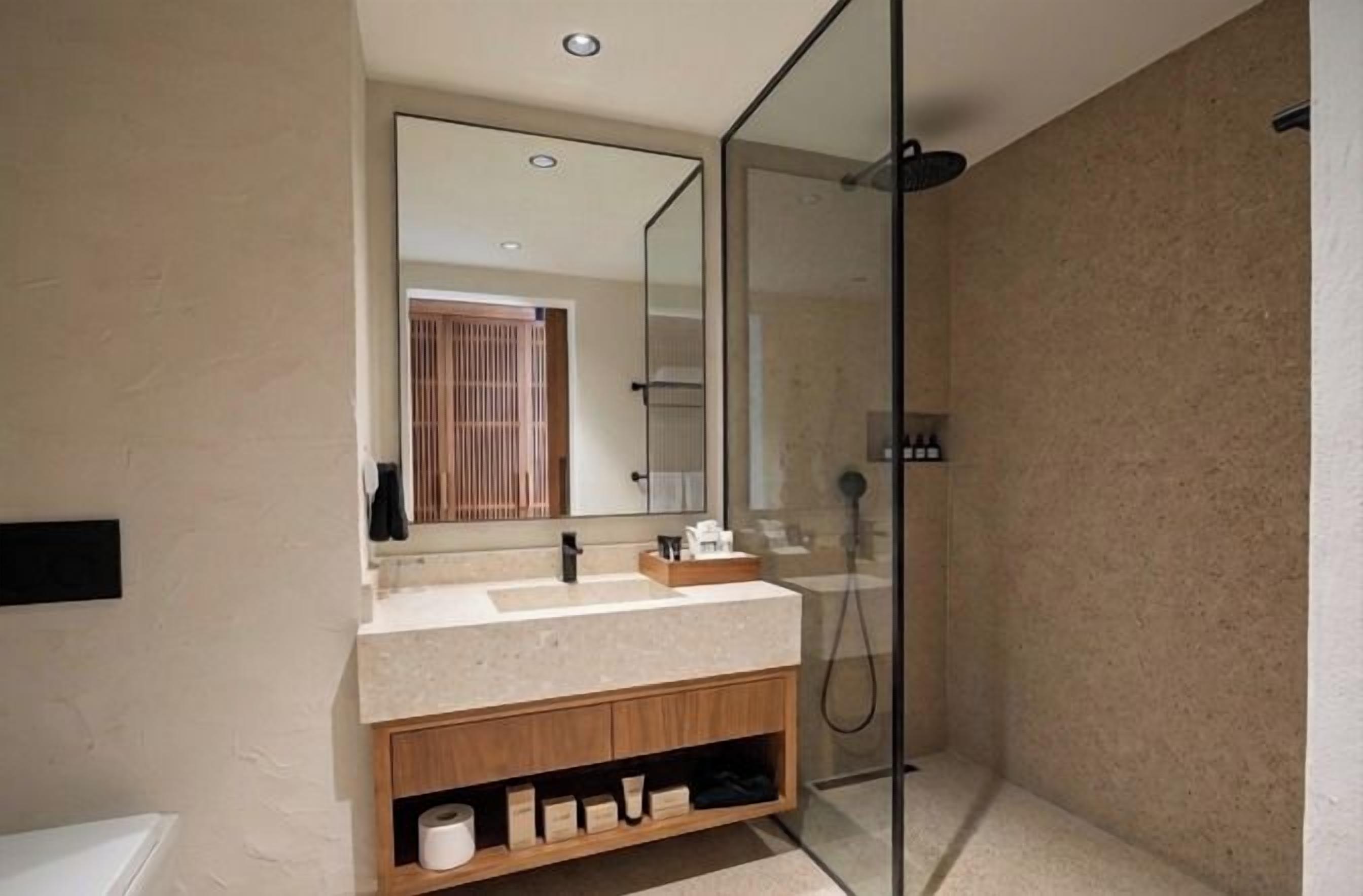 Un baño moderno con ducha de vidrio, tocador con espejo y bañera.