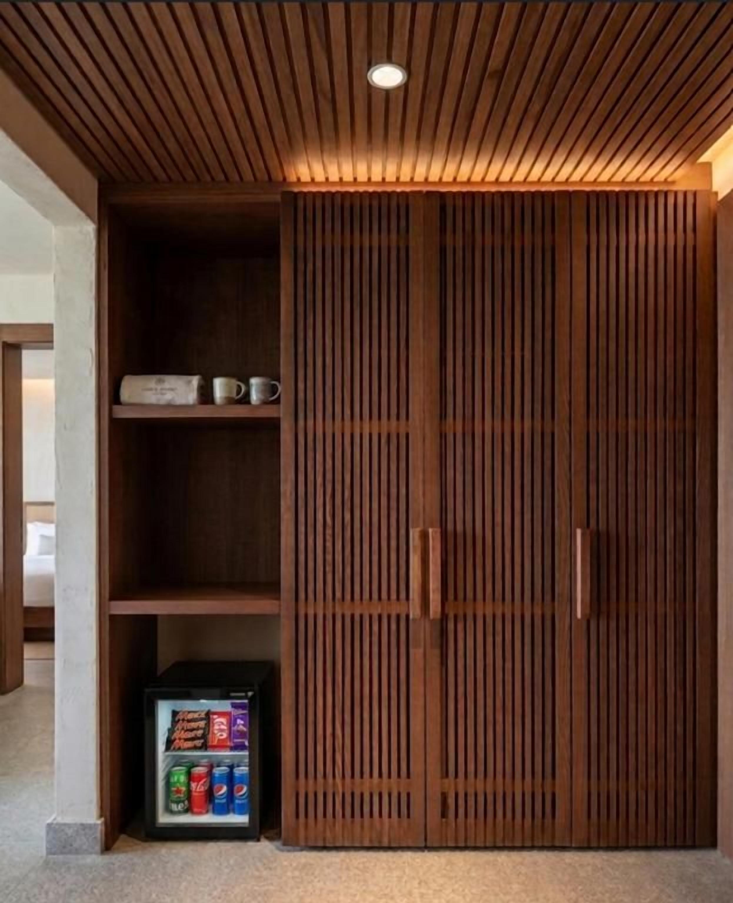Un armario de madera con un estante incorporado y un refrigerador pequeño.