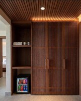 Un armario de madera con un estante incorporado y un refrigerador pequeño.