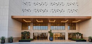 A modern building with a glass facade, large windows, and a patterned wall above.