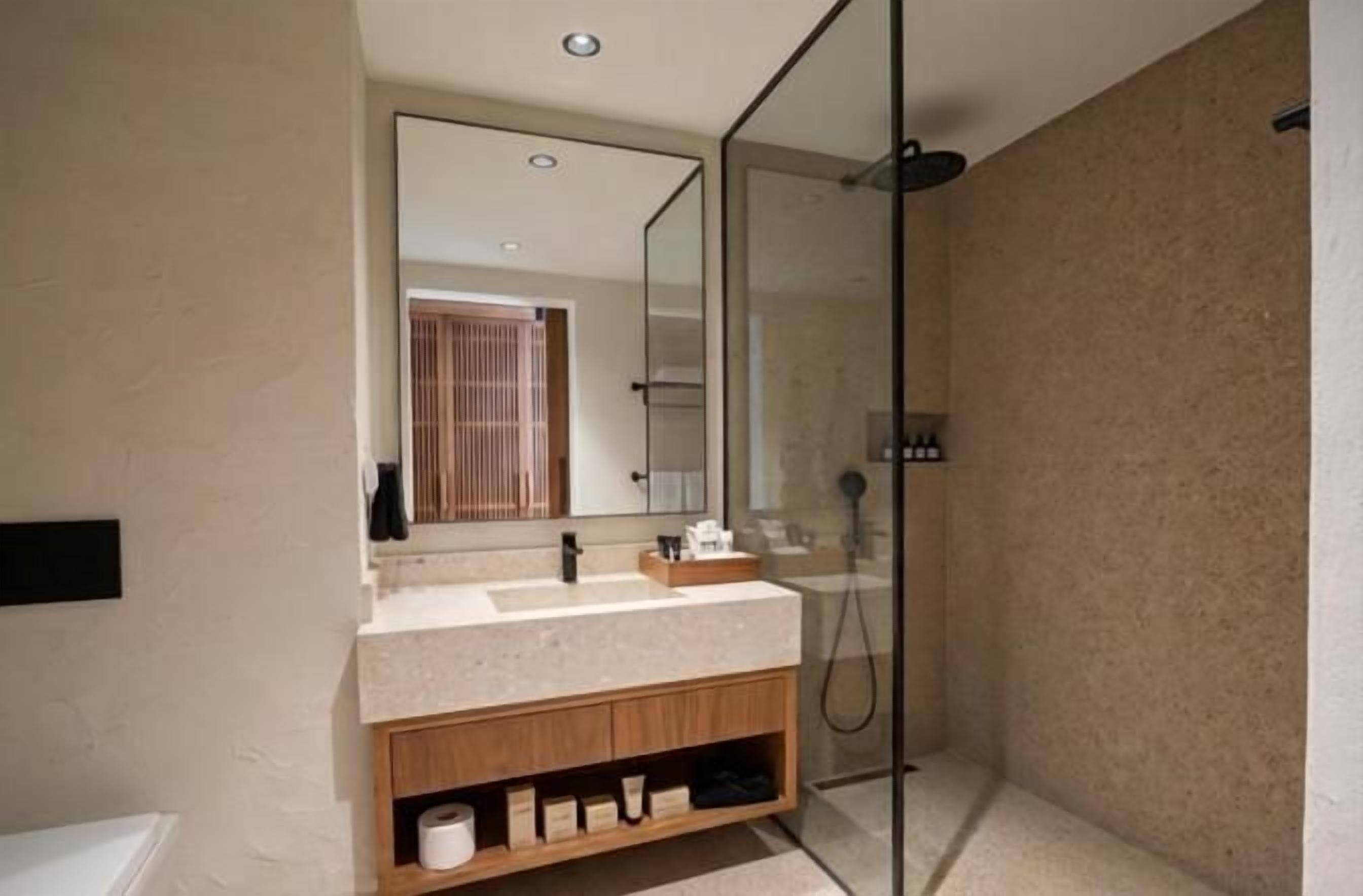 A modern bathroom with a glass shower enclosure, a vanity with a mirror, and a bathtub.