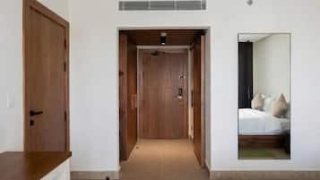 Un pasillo que da a un dormitorio con una cama y un espejo que refleja la habitación.