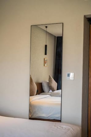 Un dormitorio con un espejo grande que refleja una cama, una lámpara colgante y un cuadro en la pared.