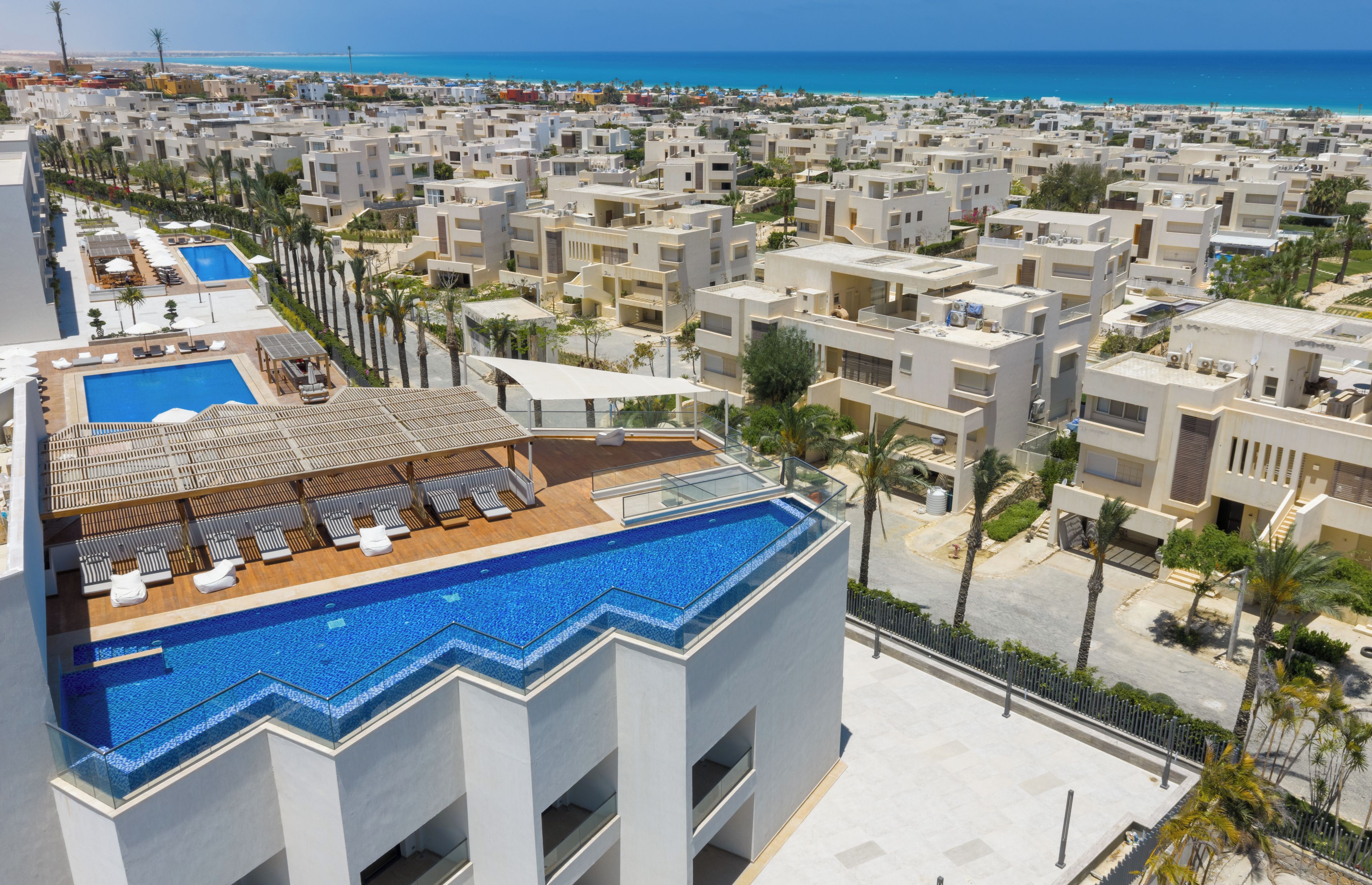 A resort with a rooftop pool and a view of the beach.