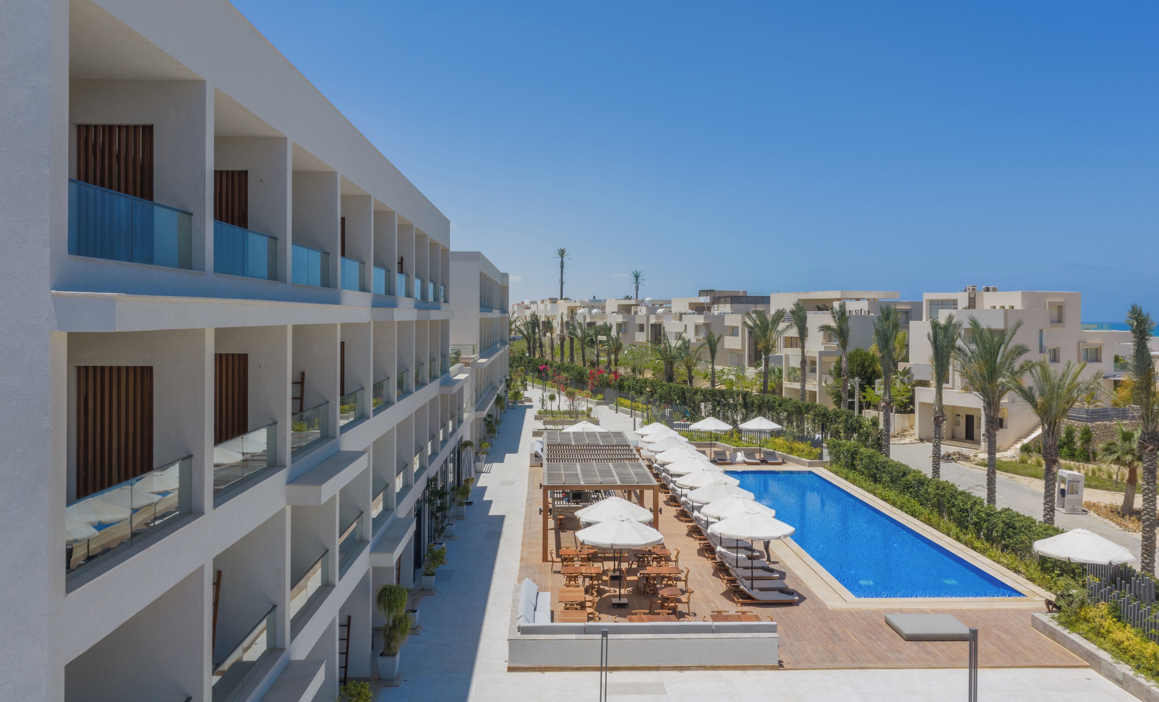 Un resort con varios balcones, piscina y mobiliario exterior.