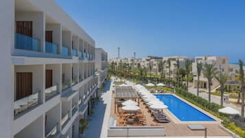 Un resort con varios balcones, piscina y mobiliario exterior.