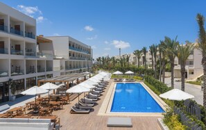 Área de piscina do resort, com espreguiçadeiras, guarda-sóis e uma piscina azul cristalina.