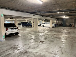 A multi-level parking garage with concrete floors and columns, several parked cars, and emergency exit signs. - Tropical Elegance - 2-Bedroom Apartment with Terrace, Walking Distance to the Beach in L'Ermitage (Saint gilles les bains)
