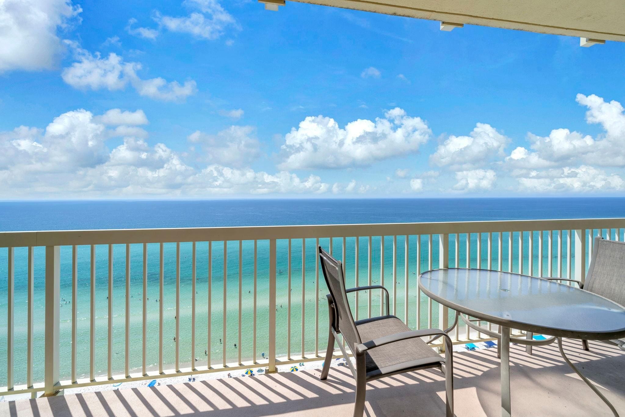 A balcony with a view of the ocean, a table, and a chair.
