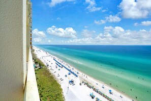 A beach with clear turquoise water, white sand, and a row of umbrellas. - Celadon 1505 - Turquoise Oasis (Panama City Beach)