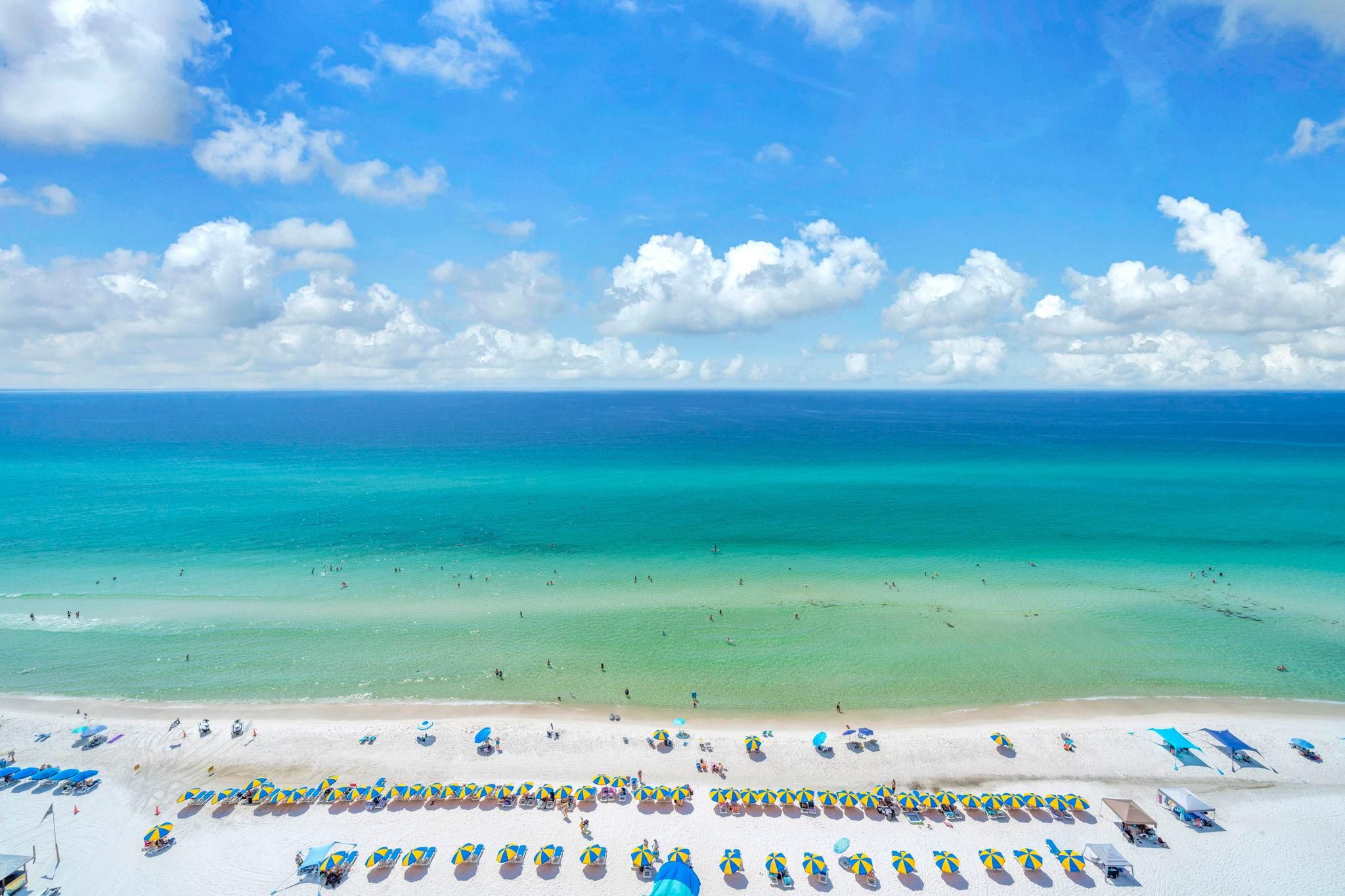 A beach with clear turquoise waters and a sandy shore.