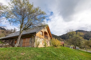Una casa de madera tradicional con techo inclinado, rodeada de césped y árboles.