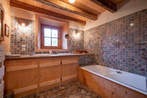 Un baño tipo cabaña de madera con una bañera grande, dos lavamanos y una ventana.